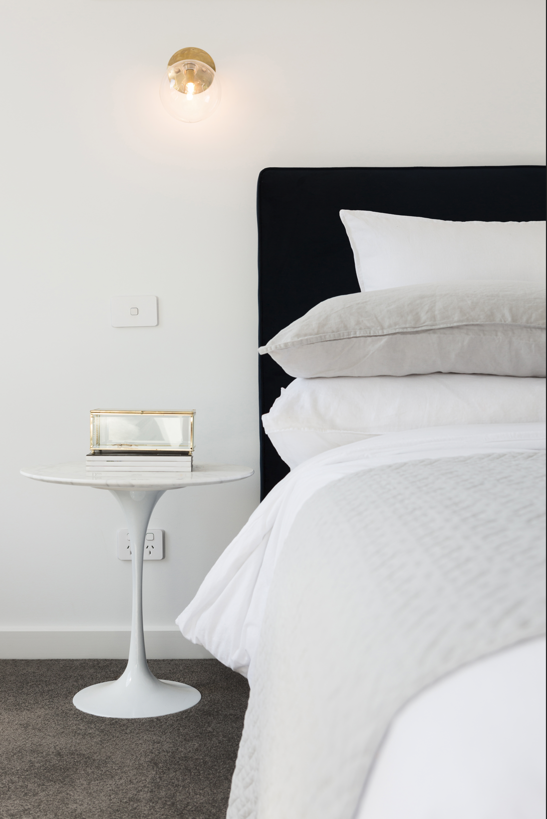 A bed with a black headboard and white linen