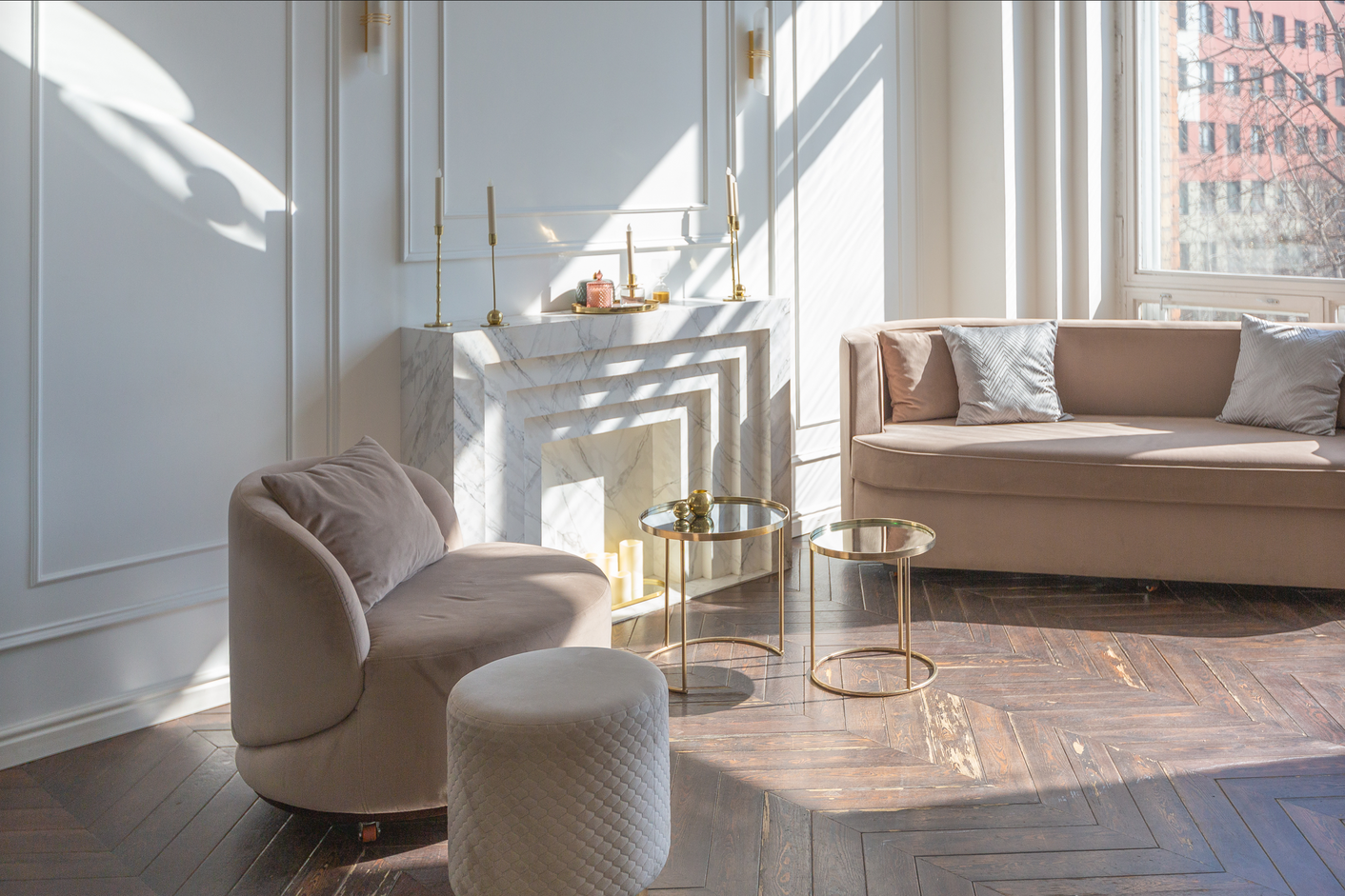 A bright white living area with a marble fireplace, and two blush pink couches